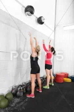 Two women throws medicine balls in fitness gym Stock Photos