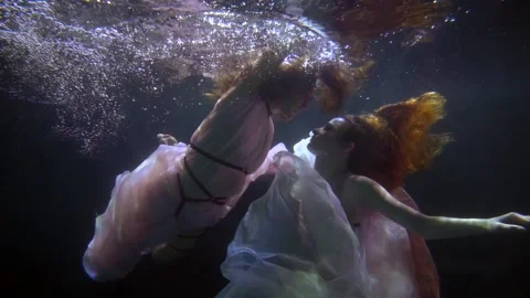 Two women in translucent dresses float in dark water Stock-Footage 195529122