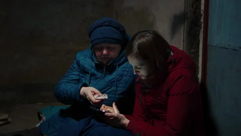 Two women using the phone when hiding in the basement Video stock 171385584