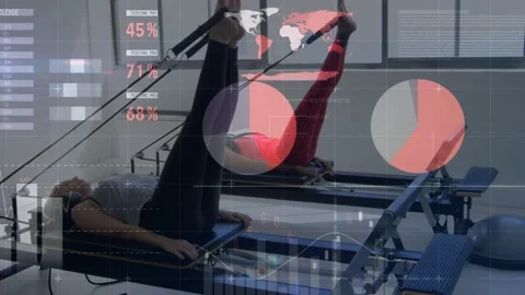 Two women using straps and doing pilates leg extension for tone, overlaid charts Stock Footage 330741579