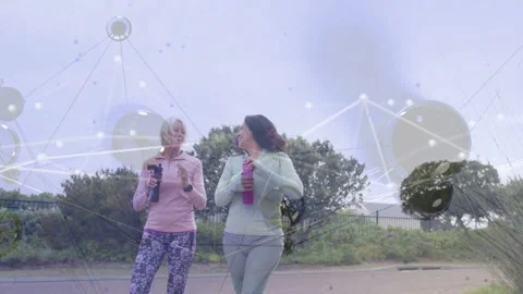 Two women walking coast path toward lens, chatting, gesturing while network Stock Footage 333610014