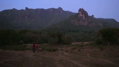 Two women walking at dusk with mountains in the distance, in Ethiopia Stock Footage 199644591