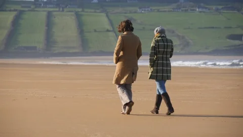 Two women walking on an empty beach talking about life. Travel and lifestyle Vídeo Stock 127518339