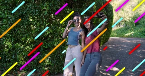 Two women walking path, pulling smartphone, capturing selfies then reviewing Stock Footage 320125546