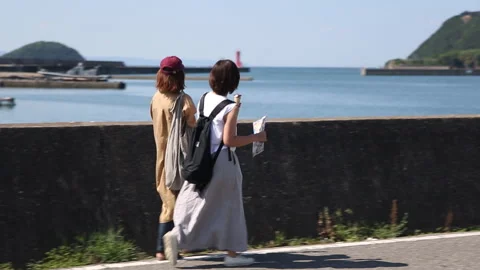 Two women walking seaside while eating ice cream Stock Footage 161810270