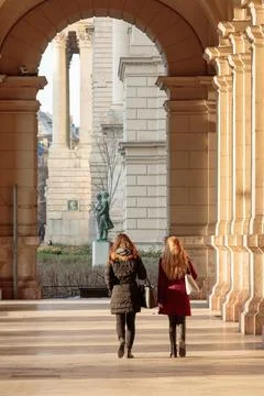 Two women walking under arches Stock Photos