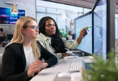Two Women Working On Computer Analyzing Data For Smart Business Decisions. Stock Photos