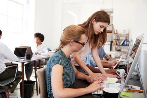 Two women working from a document in open plan office 스톡 사진