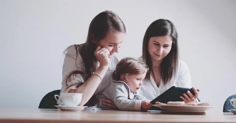 Two Women working on Laptop, holding baby girl. Slow Motion 120 fps 4K DCi. Stock Footage 63781487