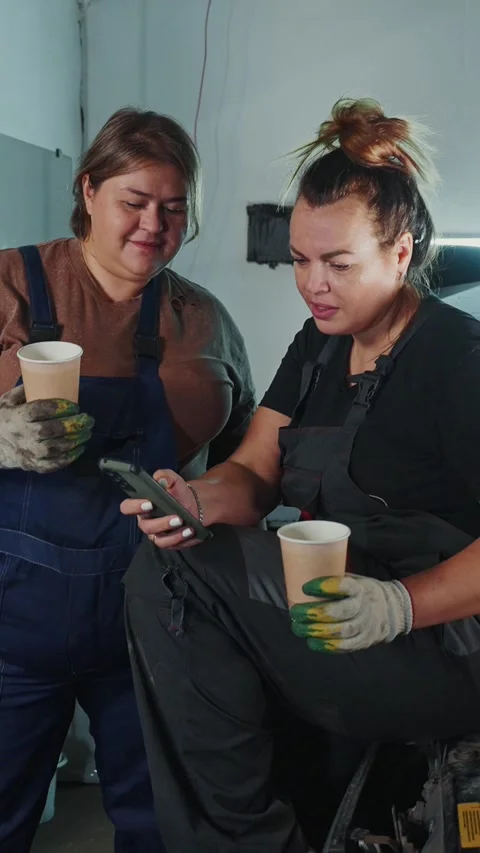 Two women working on a project while enjoying beverages in a workshop Stock-Footage 303804038