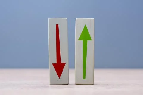 Two wooden blocks with red down arrow and green up arrow standing on a tabl.. Stock Photos