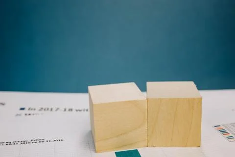 Two wooden cubes lying on a bundle of documents on a blue background Stock Photos