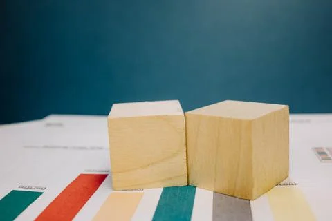 Two wooden cubes lying on a bundle of documents on a blue background Stock Photos