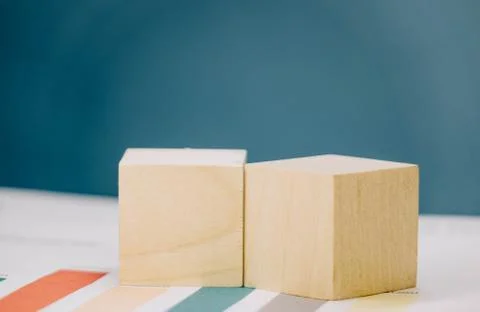 Two wooden cubes lying on a bundle of documents on a blue background Stock Photos