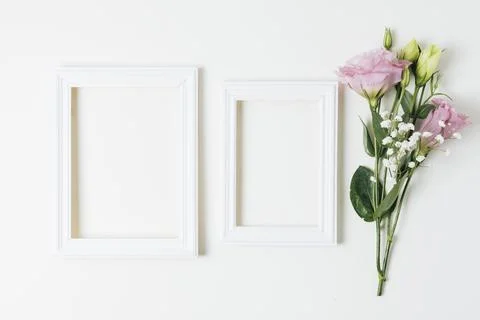 Two wooden empty frames near pink eustoma baby s breath flowers white background Stock Photos
