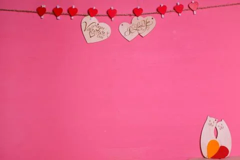 Two wooden hearts on a string Two red hearts on a clothespin on a pink backgr Stock Photos