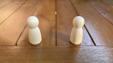 Two wooden peg figures positioned apart on a polished tabletop, Stock Photos