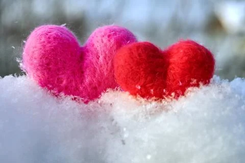Two wool red and pink hearts standing on the white fluffy snow Stockfoto's