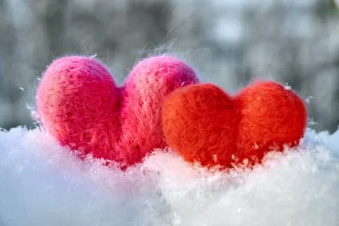 Two wool red and pink hearts standing on the white fluffy snow Stock Photos