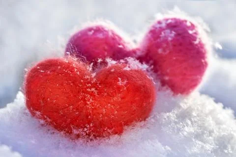 Two wool red and pink hearts standing on the white fluffy snow Stock Photos