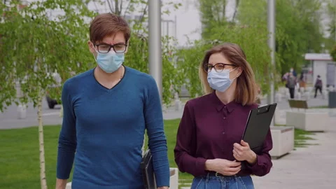 Two work colleagues in protective mask walk outside office building. Stock Footage 153500454