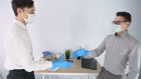 Two worker men wear shirts face masks, sit at table, keep social distance indoor Stock Footage 131471201