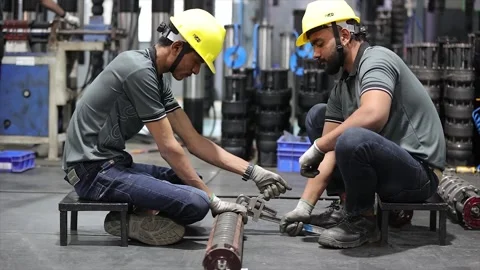 Two worker in unison to secure a cylindrical industrial pump casing on a Stock Footage 332728180