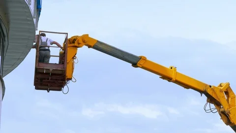 Two Workers on Aerial Platform Are Repairing Sign of Commercial Building Against Stock Footage 89323401