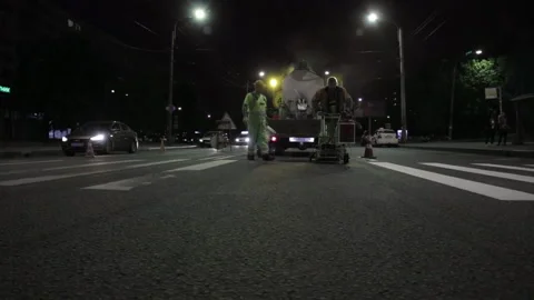 Two workers apply road markings on asphalt at night medium shot Stock Footage 221923940