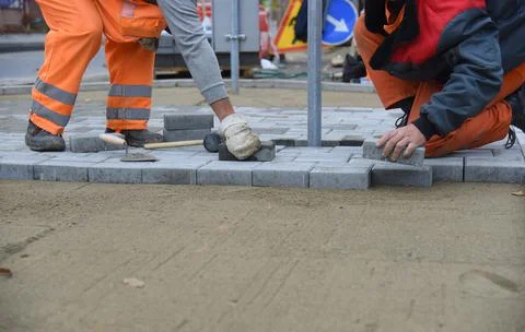 Two workers are laying paving slabs. Stock Photos