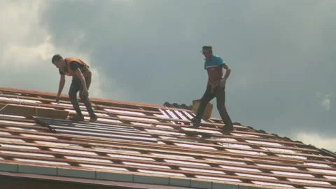 Two workers are measuring a part of metal tile at the roof top constructing Stock Footage 130248926