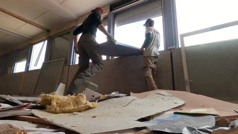 Two workers are throwing a wooden door by a window on a construction Video stock 157570555