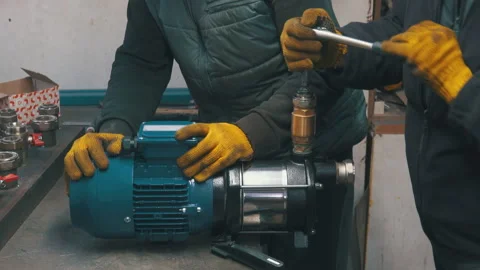 Two Workers Assembling Water Pump with Wrench Close-Up | Technicians Installing Stock Footage 343807117