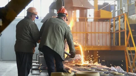 Two workers bending a metallic barrel with liquid iron flowing in containers 库存影片 156076163