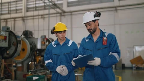 Two workers in blue uniforms stand together in a factory Video stock 338066247