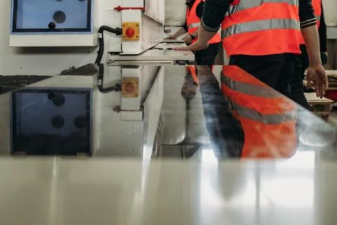 Two workers in bright safety vests are engaged in the careful manipulation of Stock Photos