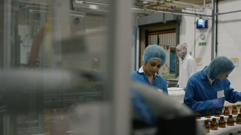 Two workers checking bottles on production line and talking in factory Stock Footage 107950728
