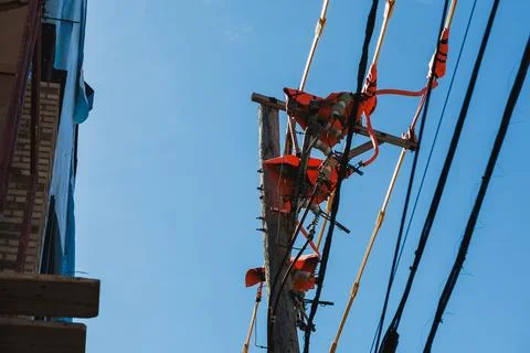 Two workers climb a utility pole to perform maintenance. They wear safety har 스톡 사진