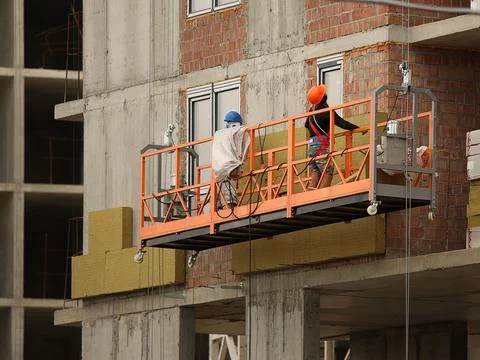 Two workers in a construction basket insulate the glassy wall of a multi-st.. Stock Photos