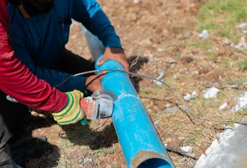 Two workers cutting pvc trough / spout for rooftop rainwater drain. Stock-Fotos