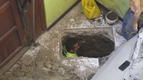 Two workers digging dirt from a hole they make in the floor Stock Footage 150671551