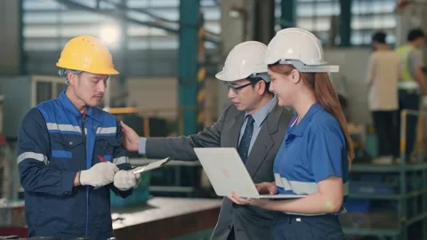 Two workers discuss machinery in a factory floor 動画素材 345135531