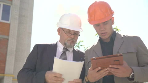 Two workers discussing scheme of building using tablet near builds. 4K 스톡 동영상 66791298