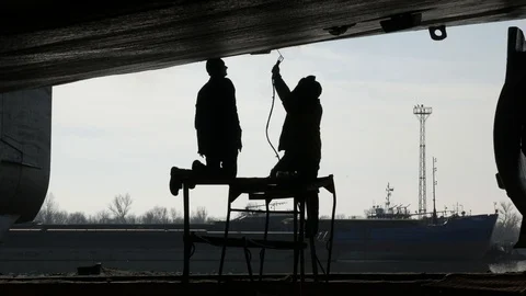 Two workers in the dock finish the electric welding job Stock Footage 87085270