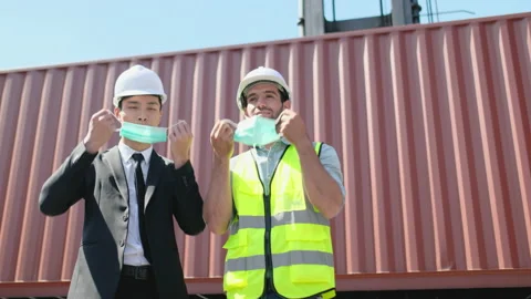 Two workers engineer and cargo container technician take off mask then thumbs up Stock-Footage 146434664