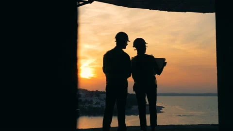 Two workers engineers are standing in the construction site during the sunset. Stock Footage
