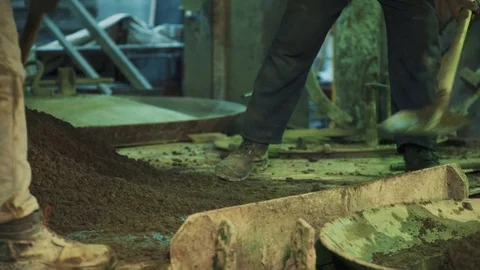 Two workers fast throw cement on metal cauldron lid at factory Stock Footage 75643037