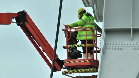 Two workers in green vests work on a crane Stock Footage 232215611