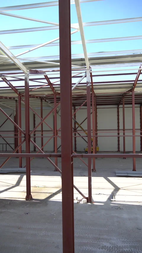 Two workers guiding sandwich panel onto hangar roof under construction, Almaty Stock Footage 335795715