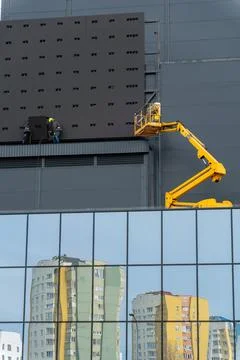 Two workers in hard hats mount elements of outdoor video advertising Stock Photos